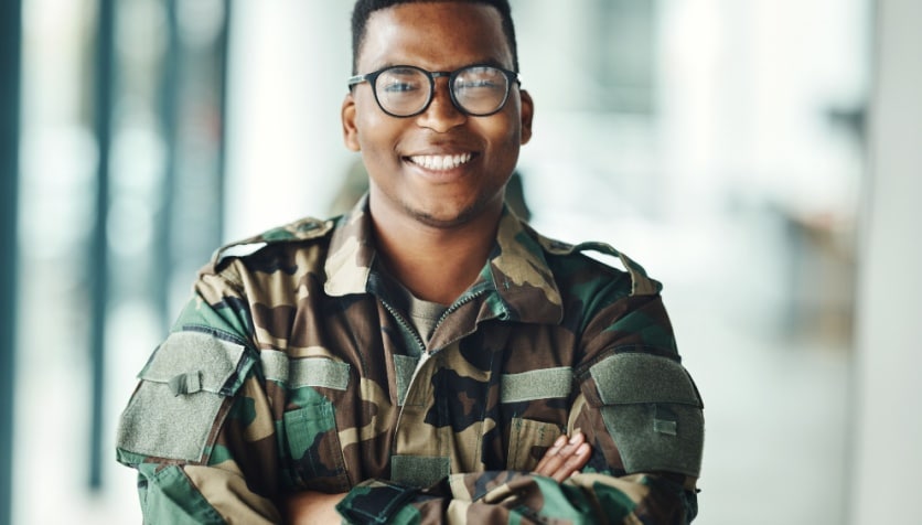 A smiling man in a military uniform wearing glasses.