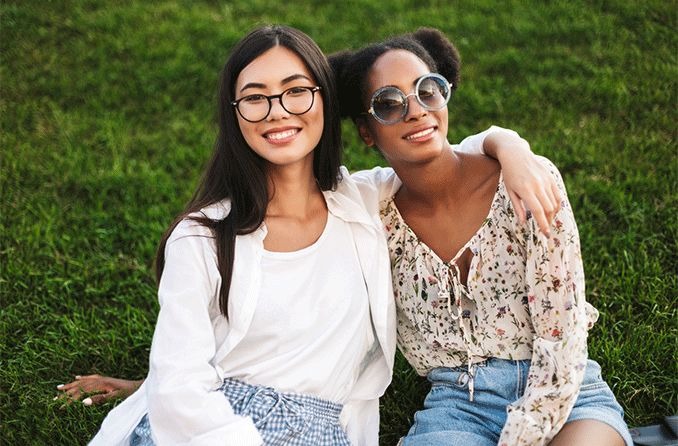 two women wearing Oliver Peoples eyewear with a grassy backdrop