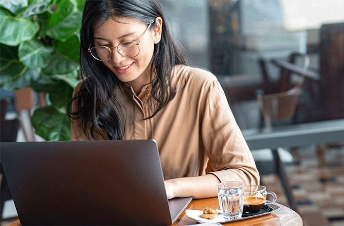 Woman wearing glasses on laptop shopping for eyeglasses on Zenni