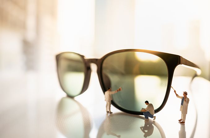 miniature men taking care of pair of sunglasses