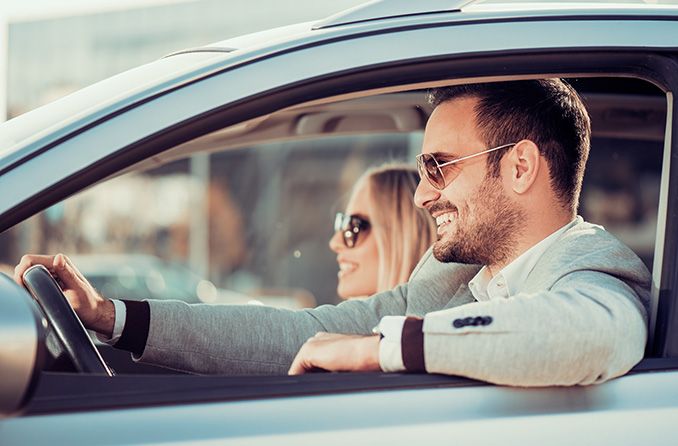 Happy couple driving in a car wearing sunglasses