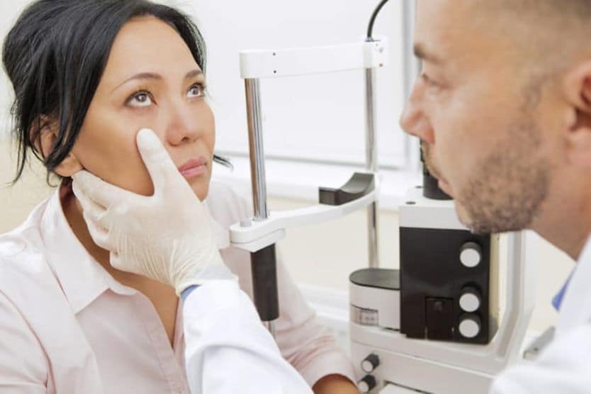 A dark-haired woman calmly looks toward the ceiling so her optometrist can examine her eyes. A dark-haired woman calmly looks toward the ceiling so her optometrist can examine her eyes.
