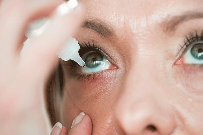 woman putting Pataday eye drops into eye woman putting Pataday eye drops into eye