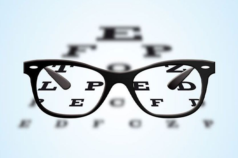 Eyeglasses with black frames positioned on an ophthalmic eye test table