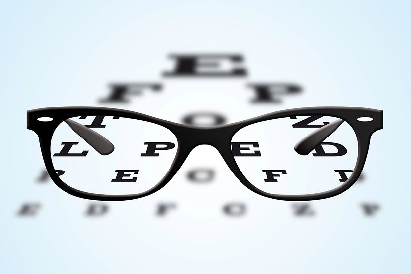 Eyeglasses with black frames positioned on an ophthalmic eye test table