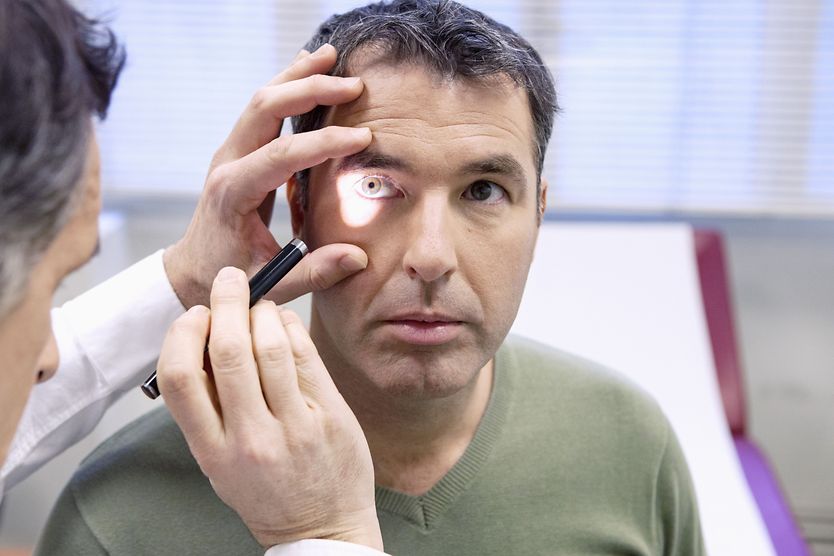 eye doctor performing a perrla eye test on patient