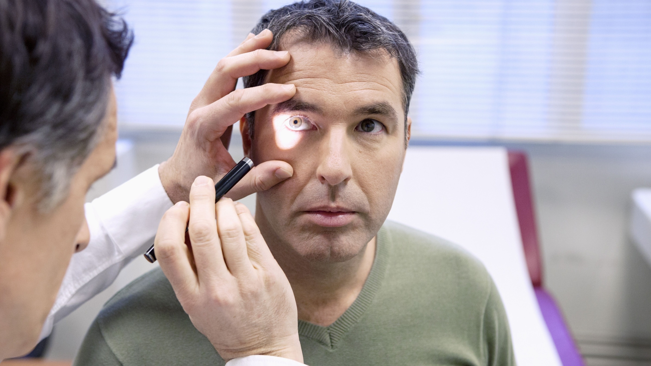 eye doctor performing a perrla eye test on patient