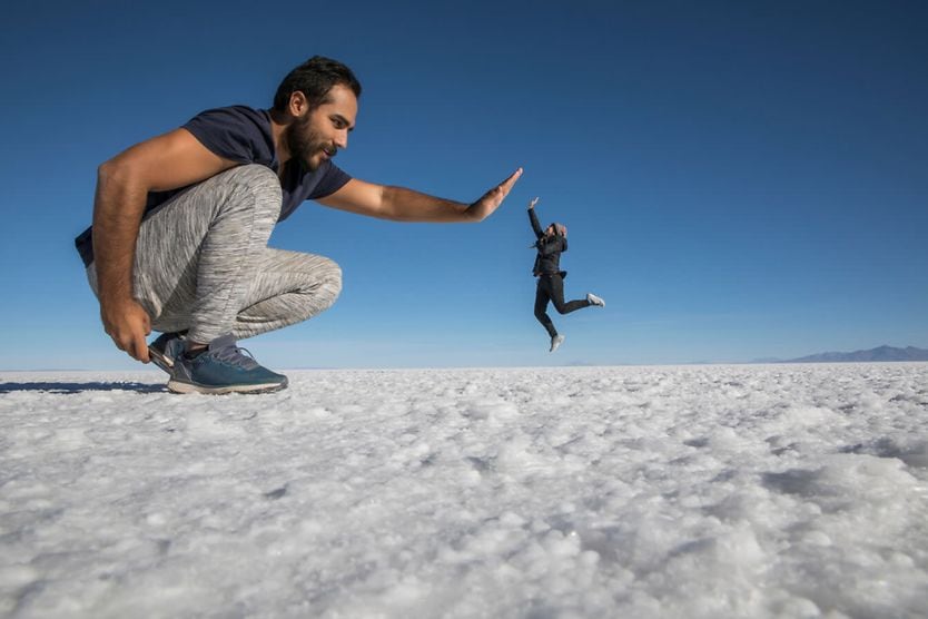 Optical illusion of giant man and small woman high-fiving.
