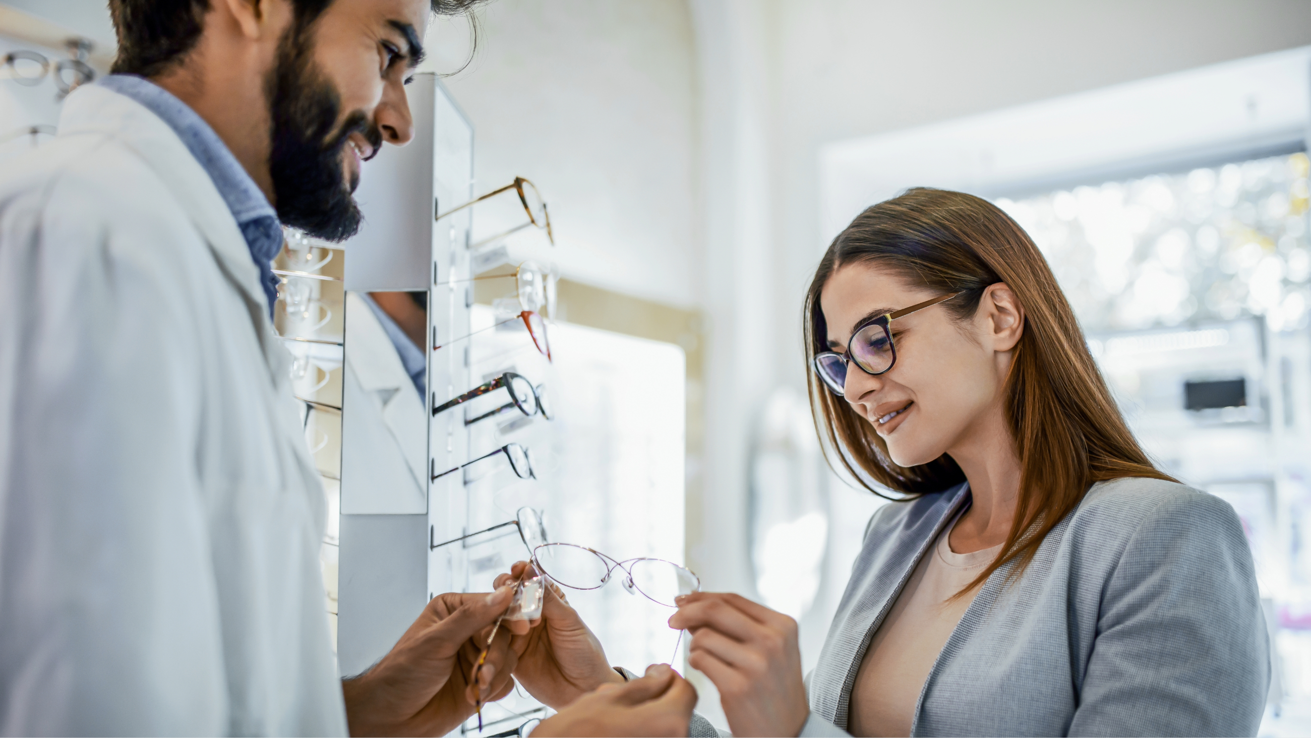 A woman with myopia wearing glasses at her optician's office wearing glasses looking at a new pair of frames.
