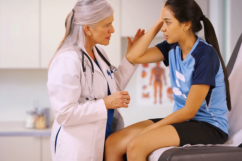 girl with a head injury getting eyes checked by a doctor