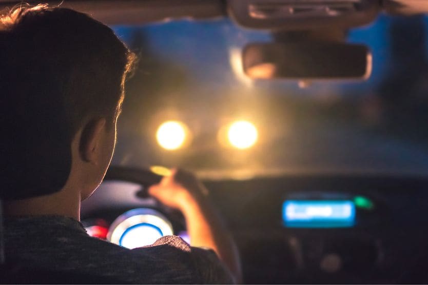 man driving at night with astigmatism looking at glaring headlights from a car driving towards him