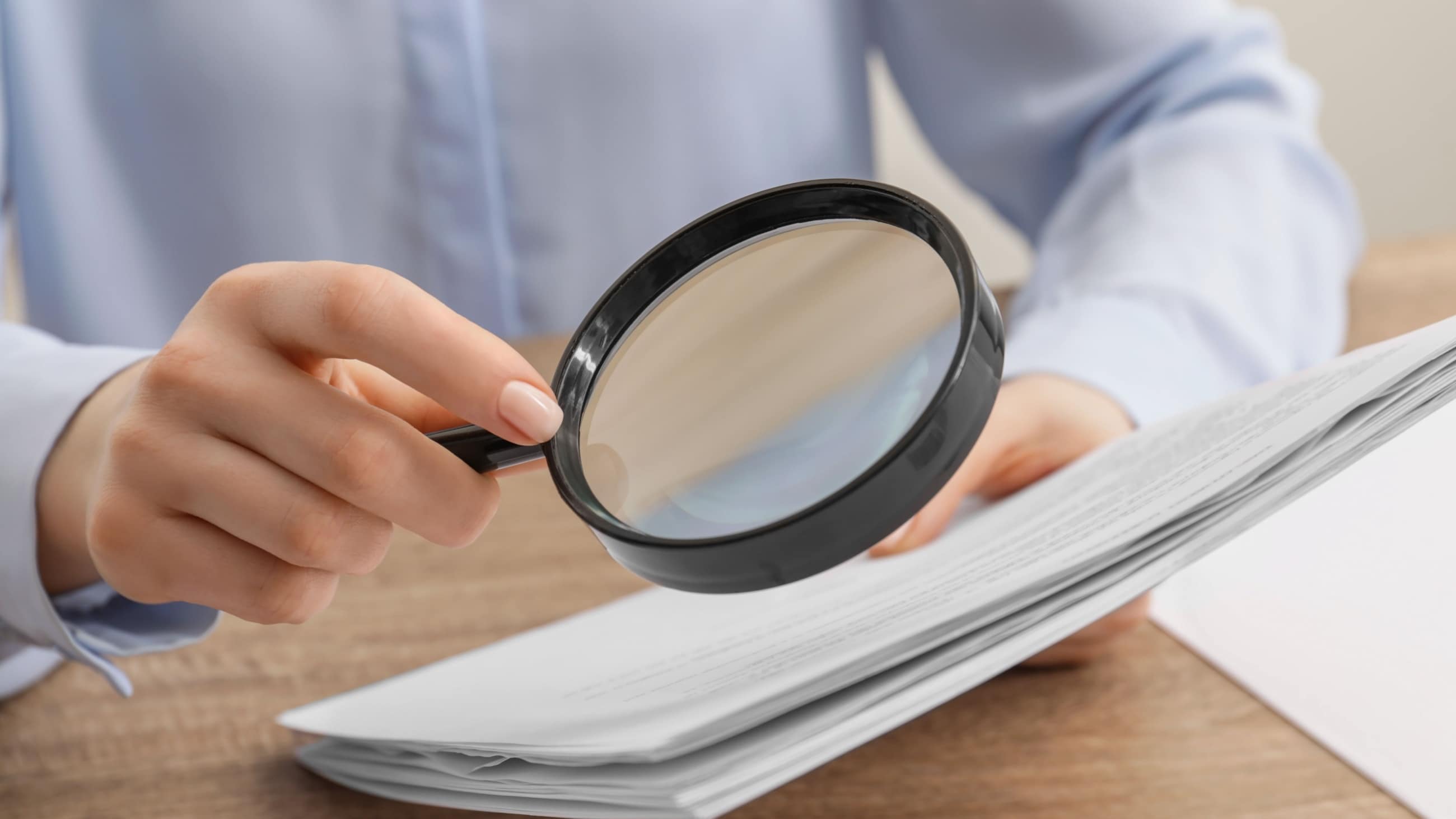 woman looking at papers through a magnifying glass woman looking at papers through a magnifying glass