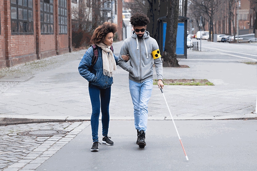 woman helping her blind friend walking with cane woman helping her blind friend walking with cane