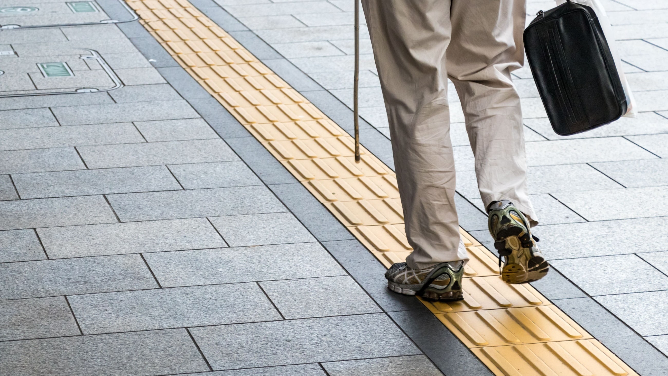 blind person walking along tactile paving
