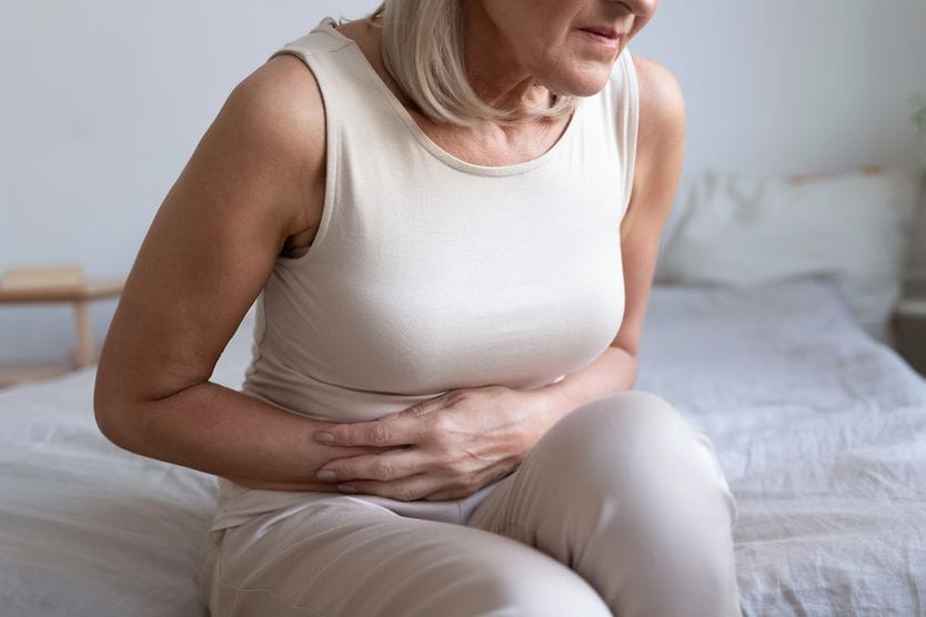 woman with poor gut health holding her stomach in discomfort woman with poor gut health holding her stomach in discomfort