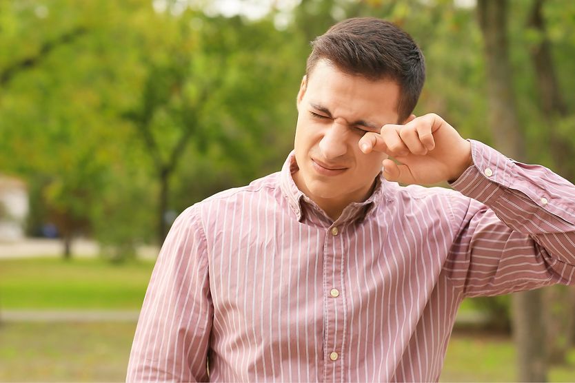 A man looks unhappy as he points to a bump on his eyelid. A man looks unhappy as he points to a bump on his eyelid.