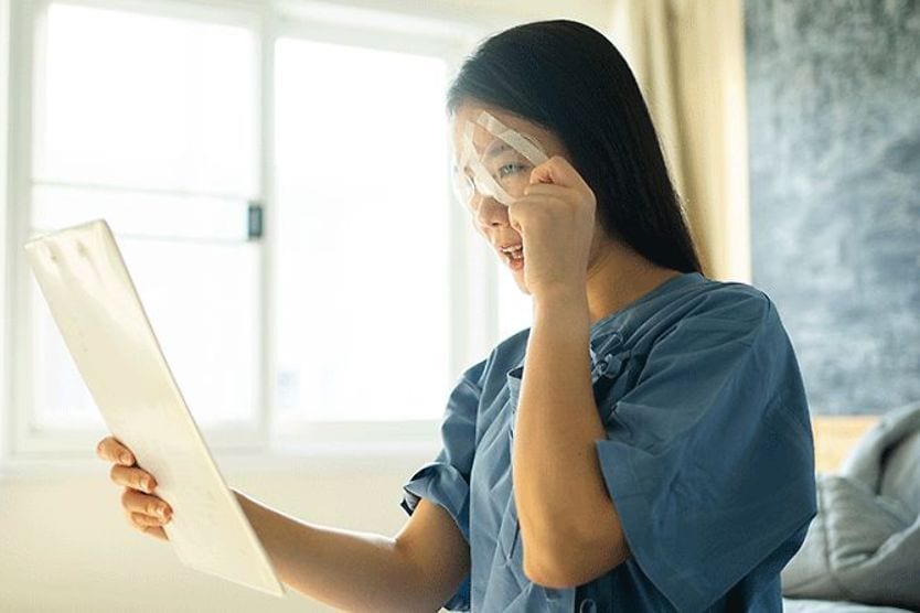 woman with blurry vision holding up something to read after having eye surgery