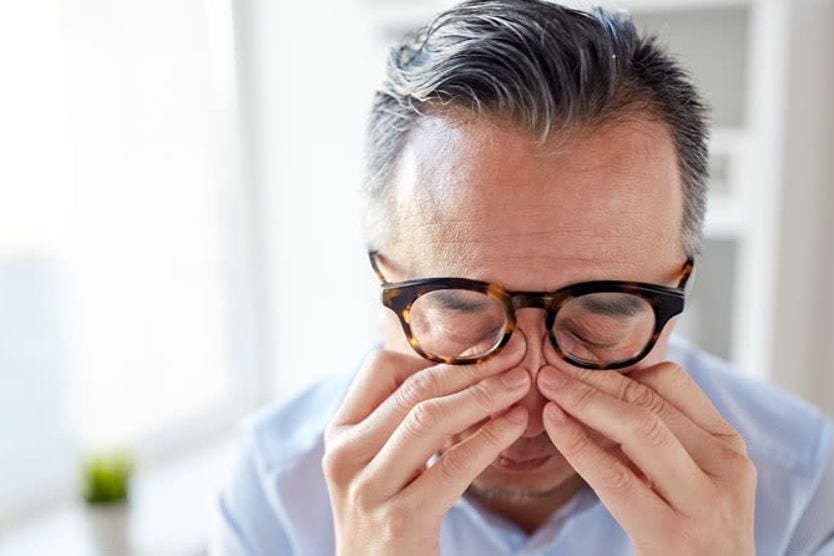 Man rubbing eyes from eye pain Man rubbing eyes from eye pain