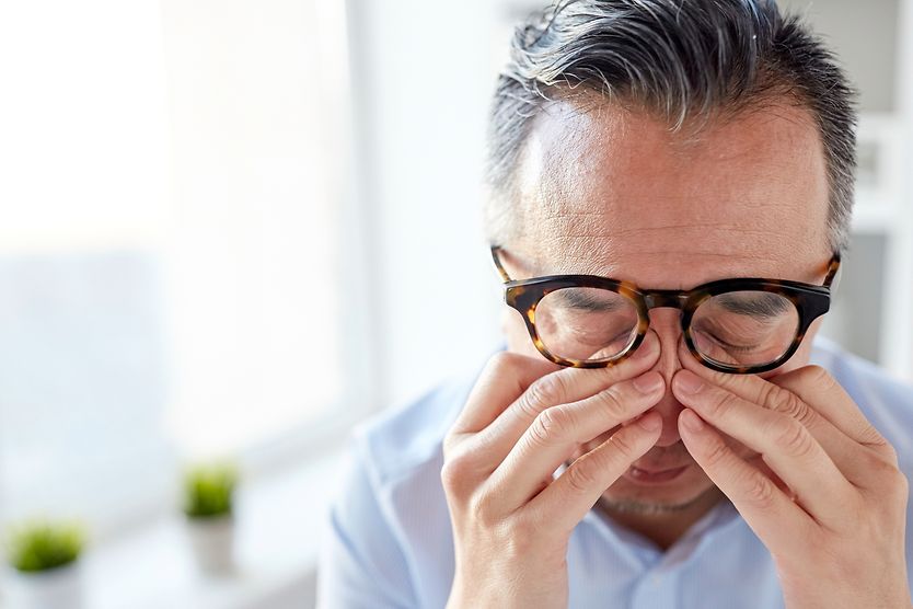 Man rubbing eyes from eye pain