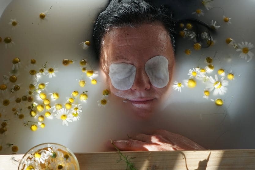 woman relaxing in a tub with compress over her eyes to naturally treat her eye floaters