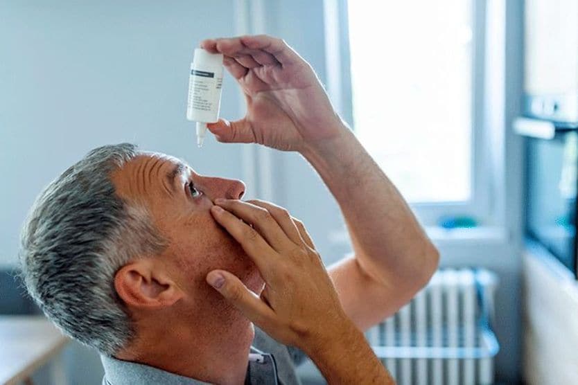 Man putting eye drops into his dry eyes Man putting eye drops into his dry eyes