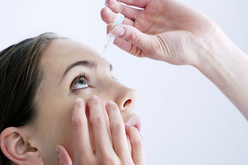 woman inserting erythromycin ointment into her eye