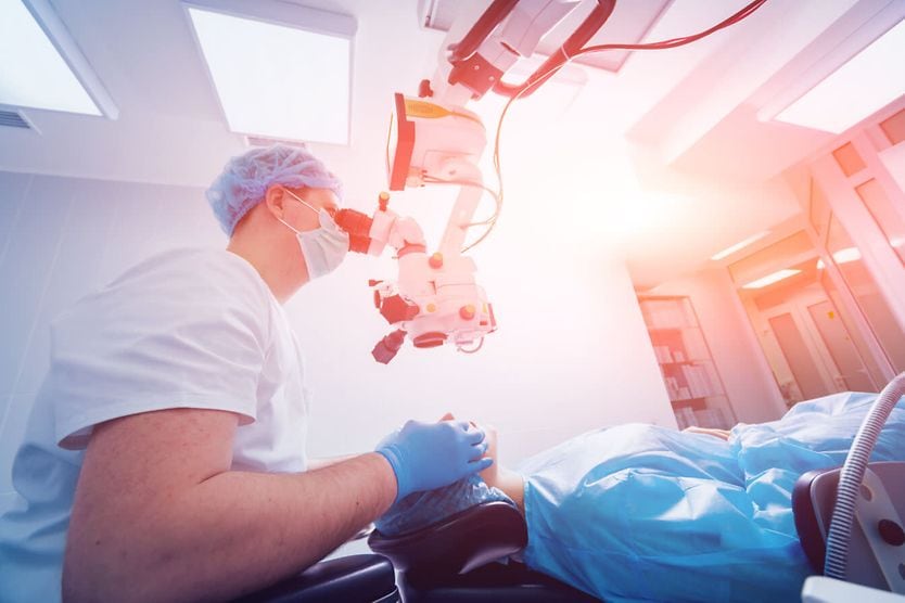 A patient and surgeon in the operating room during ophthalmic surgery. A patient and surgeon in the operating room during ophthalmic surgery.