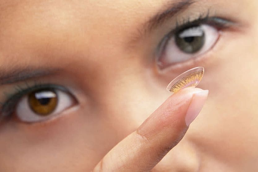 woman putting in colored contacts for her astigmatism