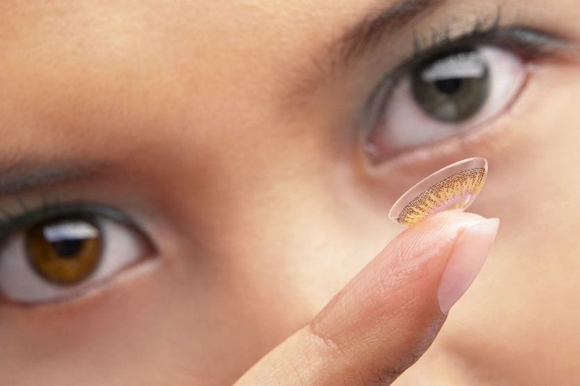 woman putting in colored contacts for her astigmatism