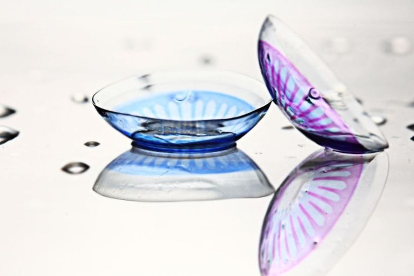 Two colored contact lenses, one for blue eyes and one for purple eyes.