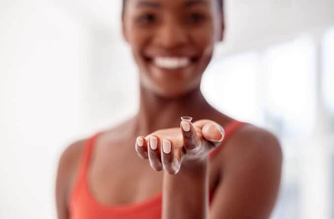 Woman holding contact lens on fingertip