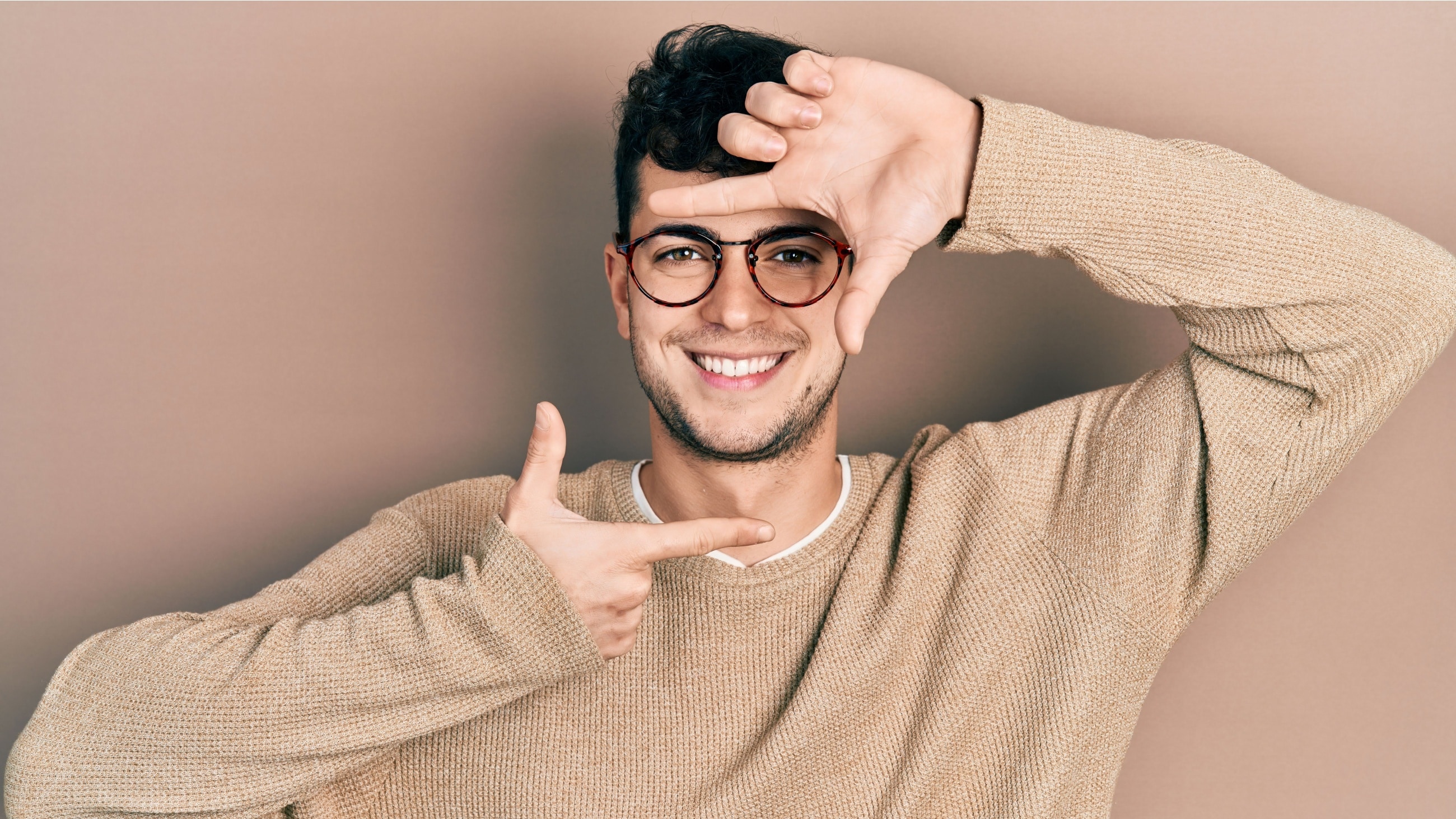 man framing his face shape with his fingers
