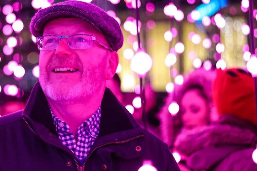 Middle-aged man wearing progressive lensed eyeglasses while looking at holiday lights Middle-aged man wearing progressive lensed eyeglasses while looking at holiday lights