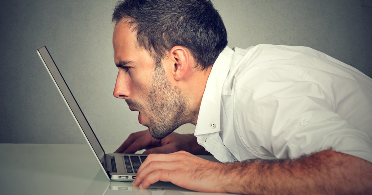 Man squints at laptop screen without reading glasses