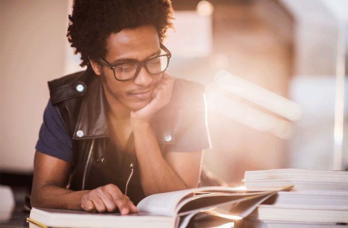 man wearing Foster Grant reading glasses while reading a book