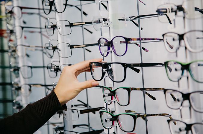 Woman choosing a pair of eyeglasses from the display