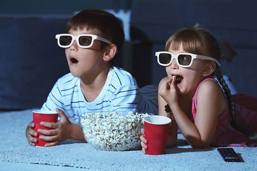 kids with popcorn watching a movie wearing 3d glasses kids with popcorn watching a movie wearing 3d glasses