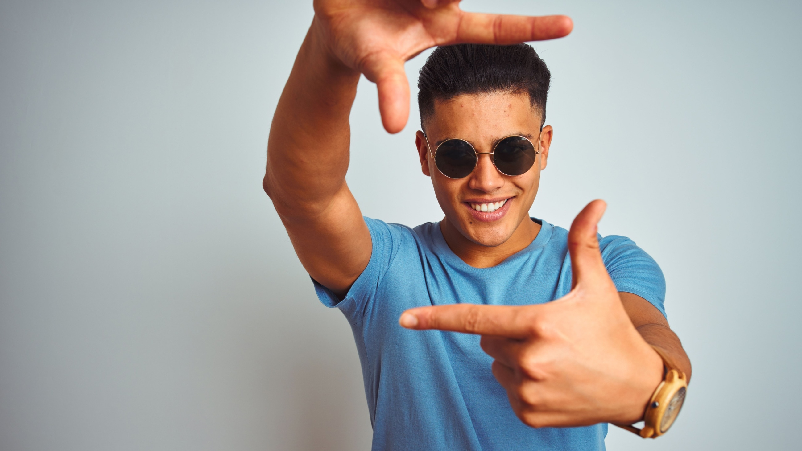 man wearing sunglasses with his fingers extended out to frame his face