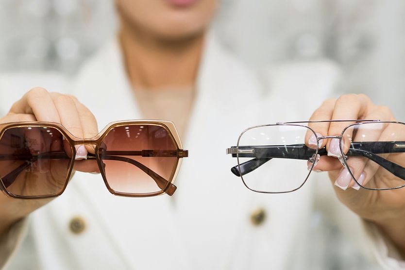 woman holding sunglasses and glasses in hands