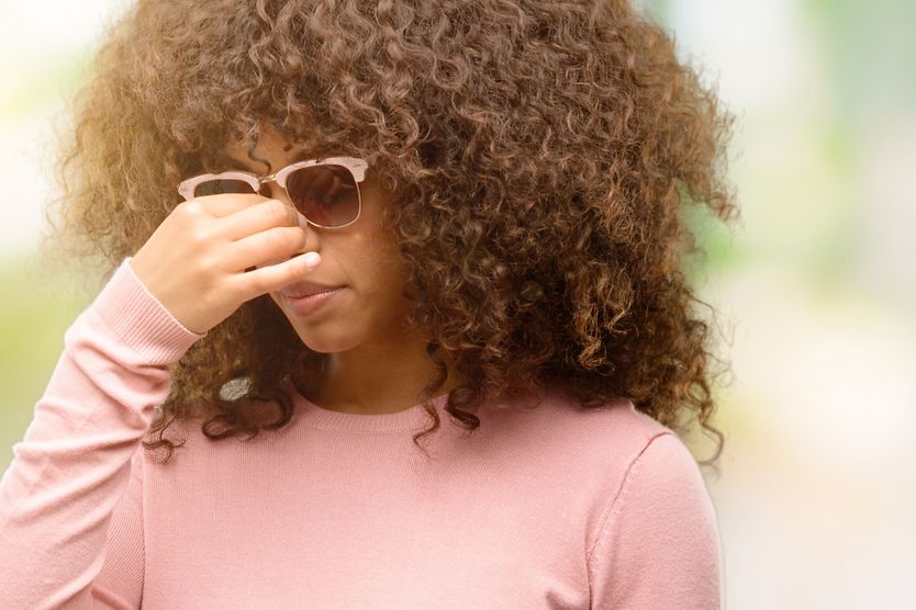 woman allergic to her sunglasses rubbing bridge of nose
