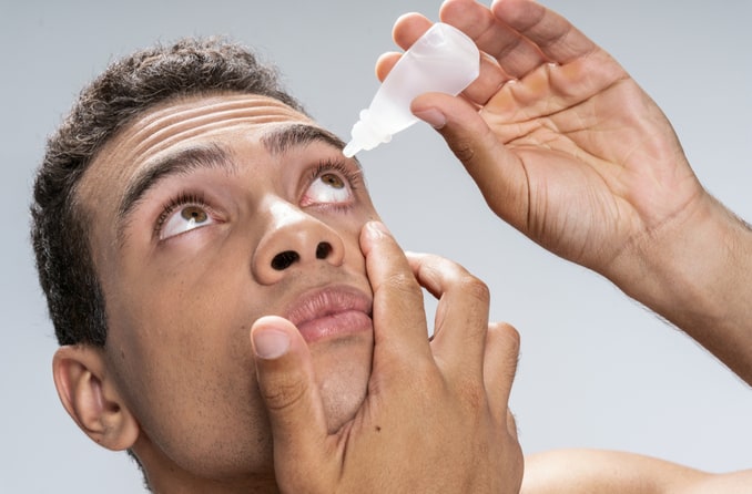 Hombre inclinando la cabeza hacia atrás para aplicar gotas para los ojos