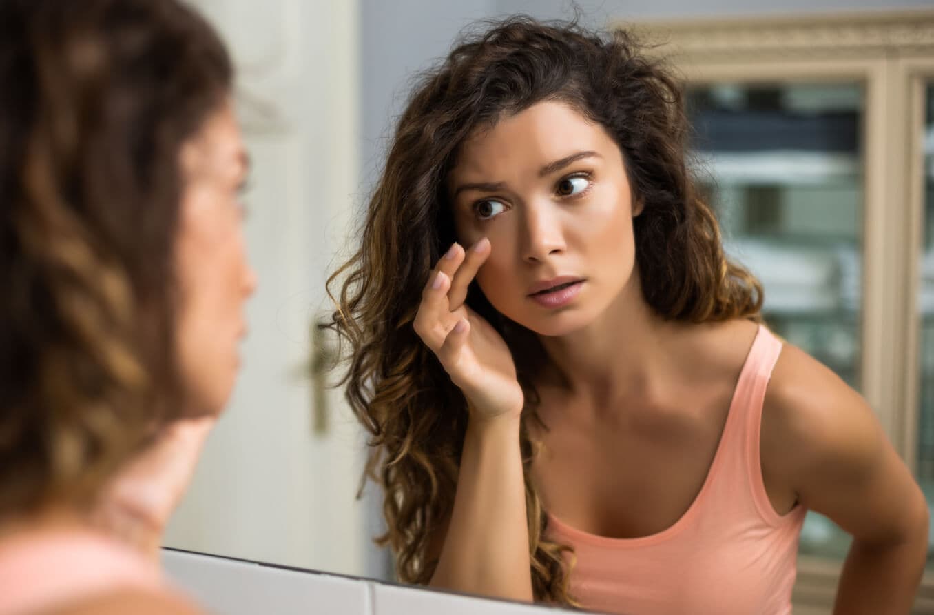 Niño tratando su párpado hinchado con una compresa fría Niño tratando su párpado hinchado con una compresa fría
