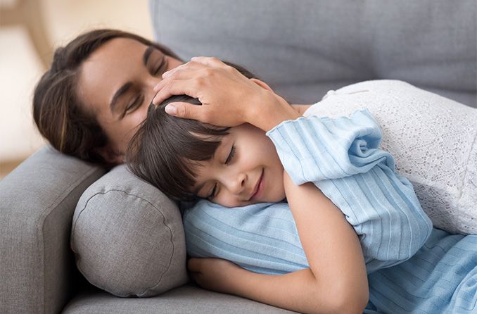 madre e hija descansando sus ojos en el sofá de casa