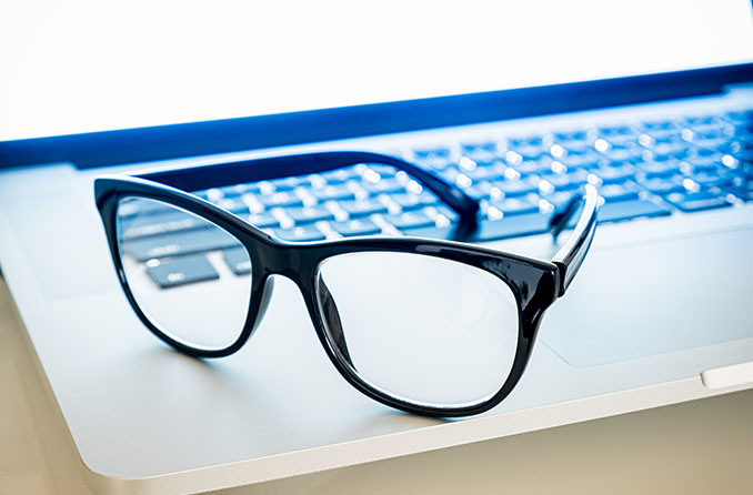 Par de anteojos de luz azul sentado en una computadora portátil