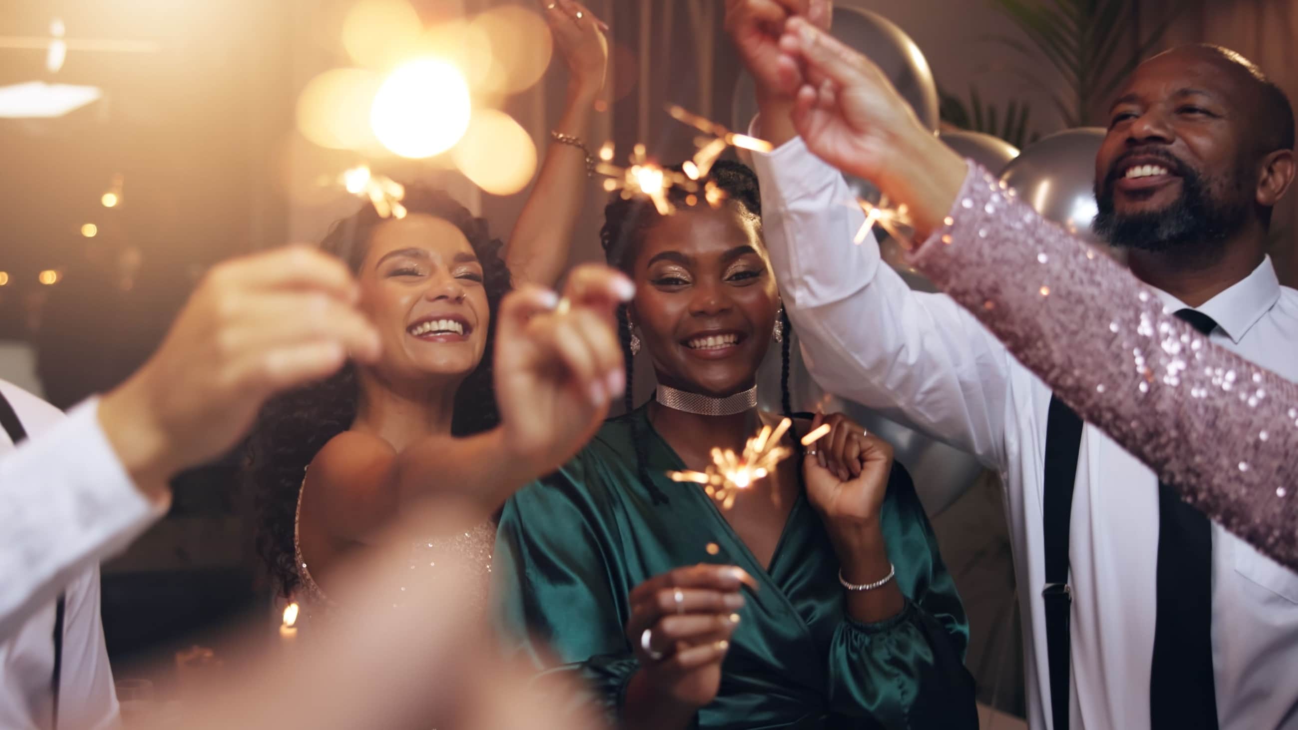 Group of people holding sparklers at a party Group of people holding sparklers at a party