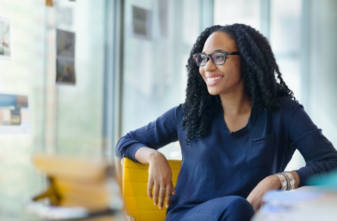 personne souriante avec des lunettes regardant par la fenêtre