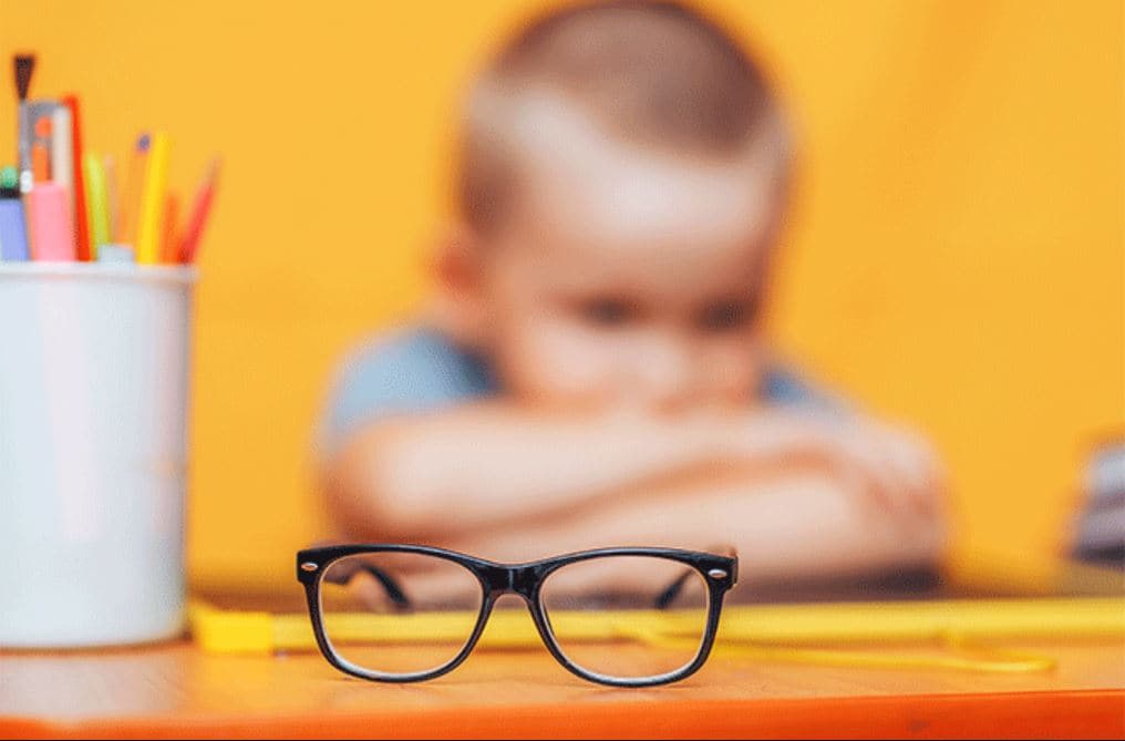 unhappy child with head down next to glasses