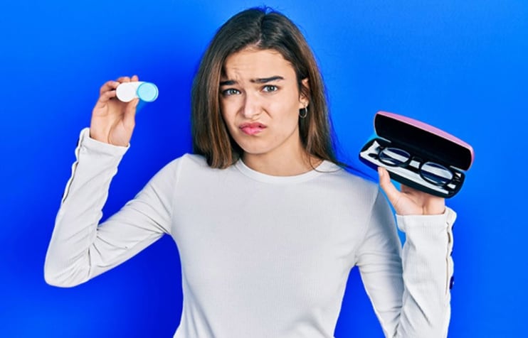 Teen girl holding contact lens case and glasses in the other hand