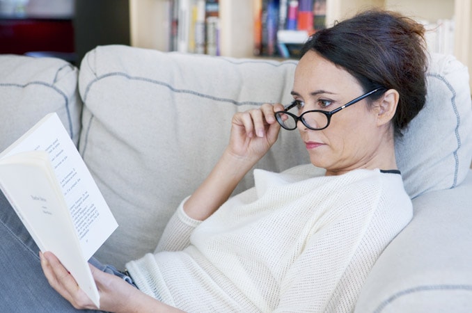 Donna con occhiali da vista che legge un libro Donna con occhiali da vista che legge un libro