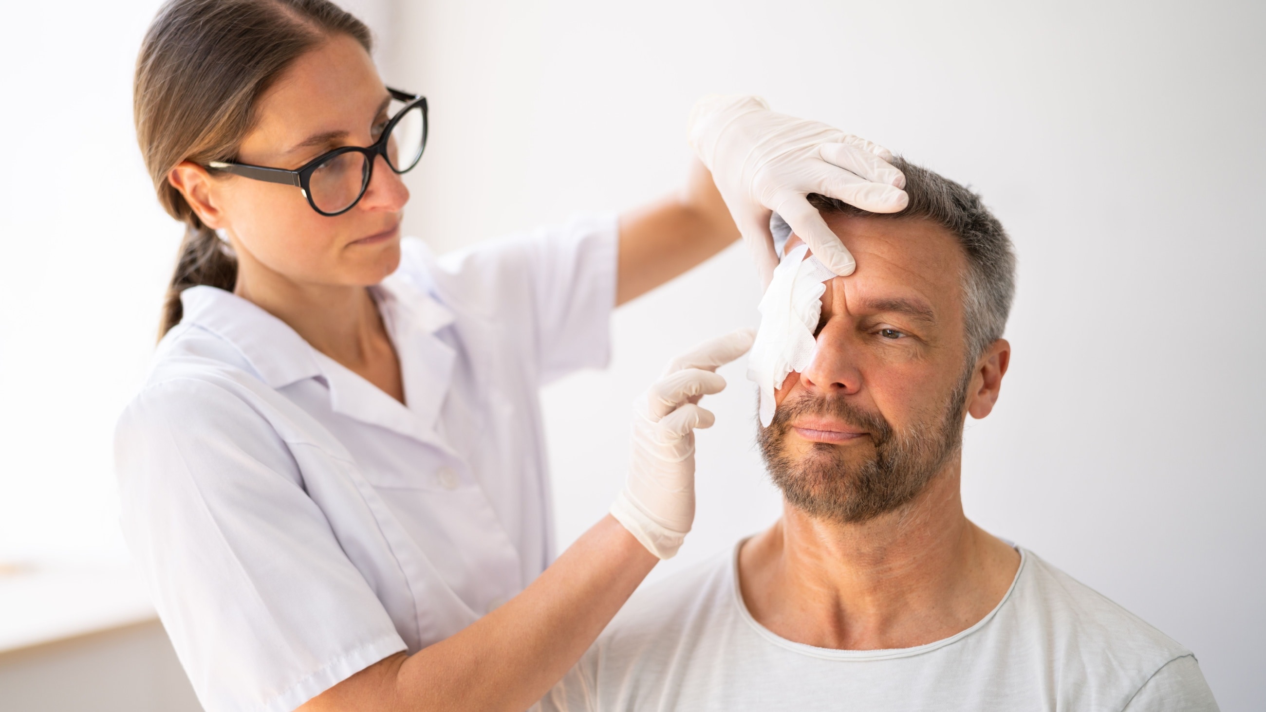 Medico che benda l'occhio di un uomo ferito Medico che benda l'occhio di un uomo ferito
